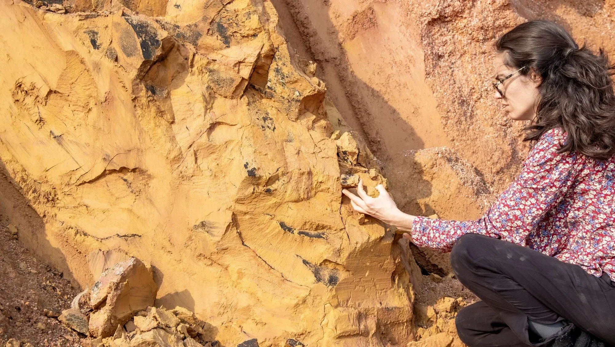 Marcela coletando pigmento ocre em um barranco de terra amarela