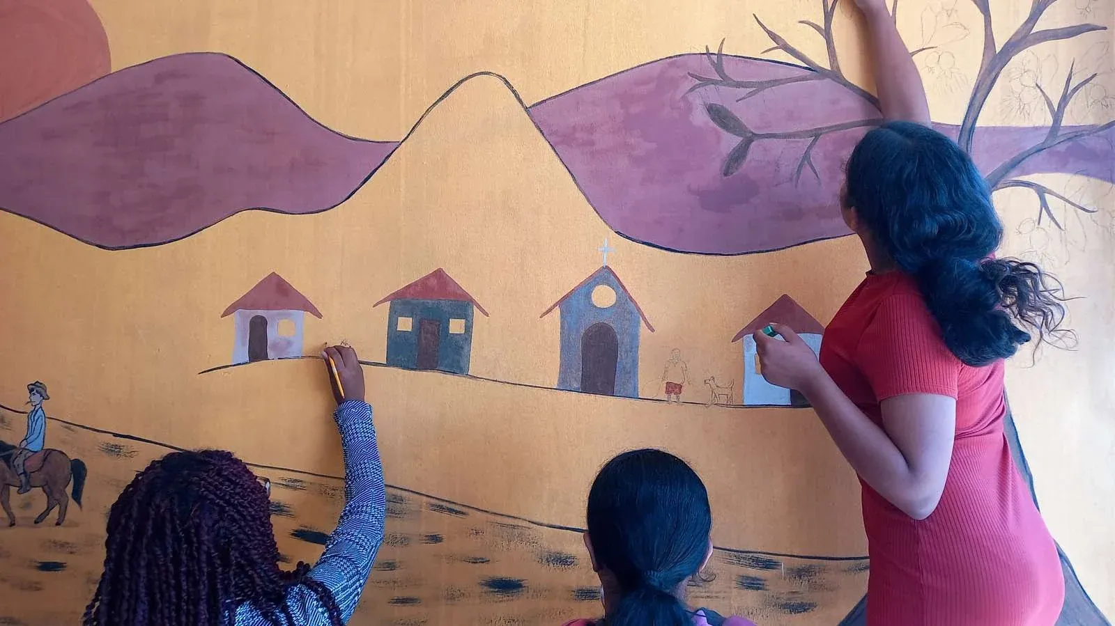 Estudantes pintando mural coletivo com tintas de terra em Mutum, Minas Gerais